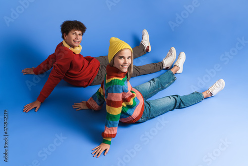 White girl and boy smiling and looking at camera while sitting on floor
