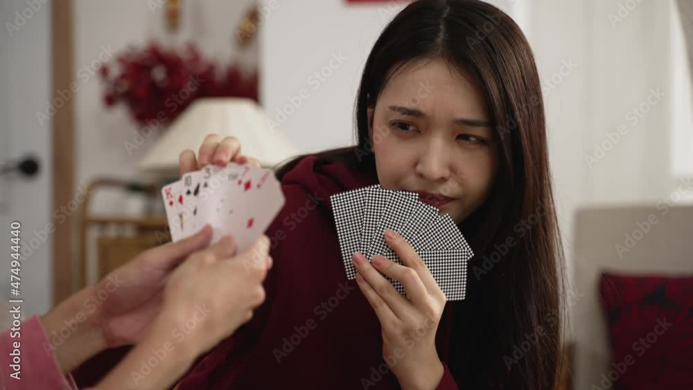 closeup of hesitant daughter feeling happy about picking the right card while playing poker game with family at home during spring holiday closeup of hesitant daughter feeling happy about picking the right card while playing poker game with family at home during spring holiday