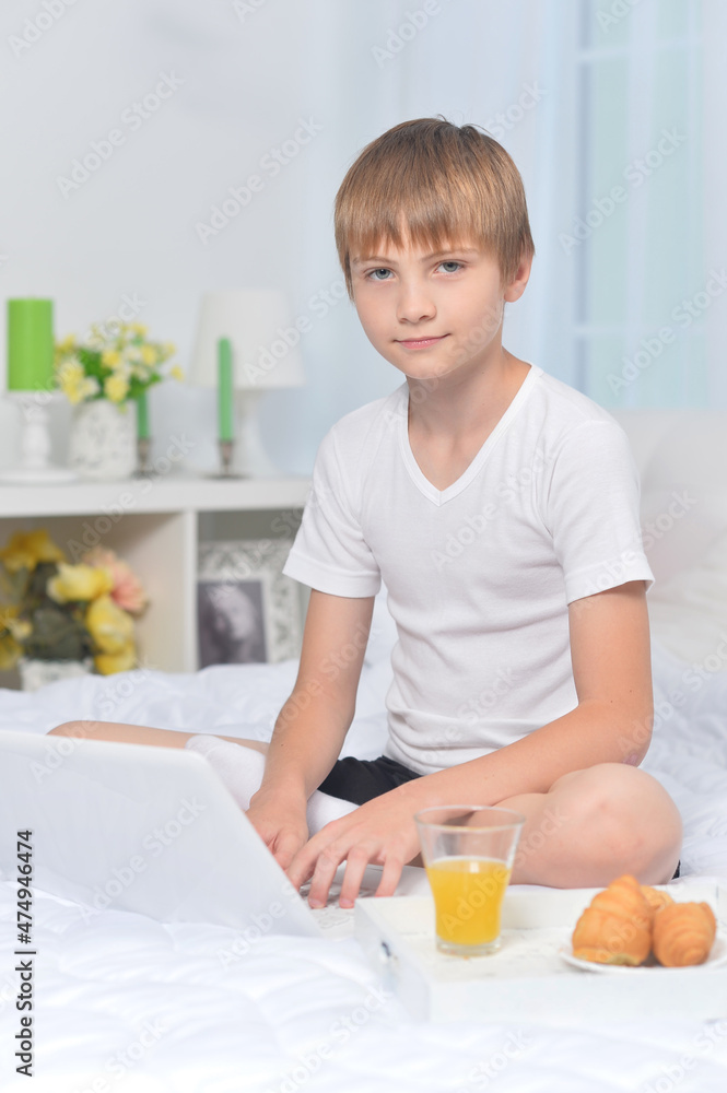 portrait of boy with laptop on bed in the morning portrait of boy with laptop on bed in the morning