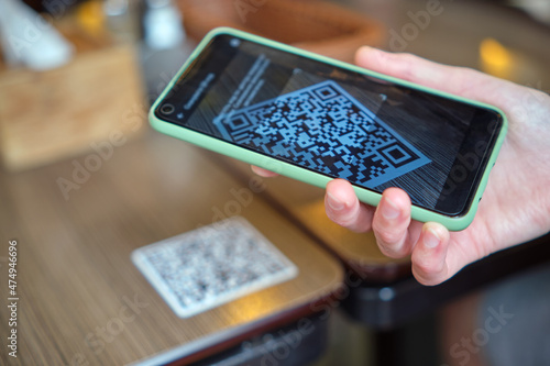 Closeup of guest hand ordering meal in restaurant while scanning qr code with mobile phone for online menu