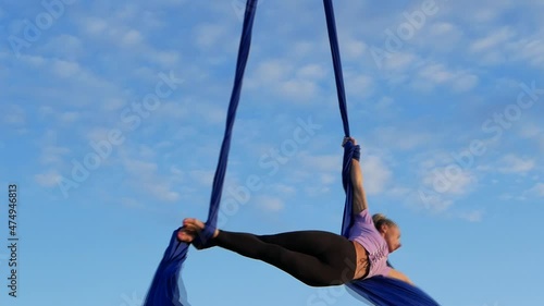 Aerial gymnastics on canvas. Slim, beautiful, athletic, tanned woman - fitness model performs gymnastic exercises in the open air.