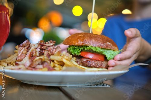 Closeup of tasty burger and french fries with meat on plate in restaurant