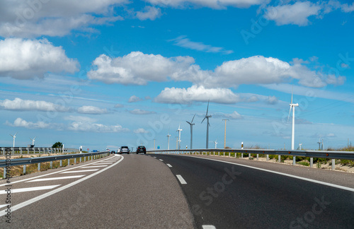 View of Wind Turbine Next to Spanish Highway With Cloudy Skies © porqueno
