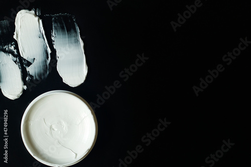 White strokes of cream or masks for all types of skin or hair with a jar isolated on a black background.