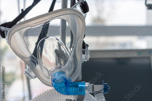 Non-invasive ventilation face mask, close up view, on background medical ventilator in ICU in hospital.