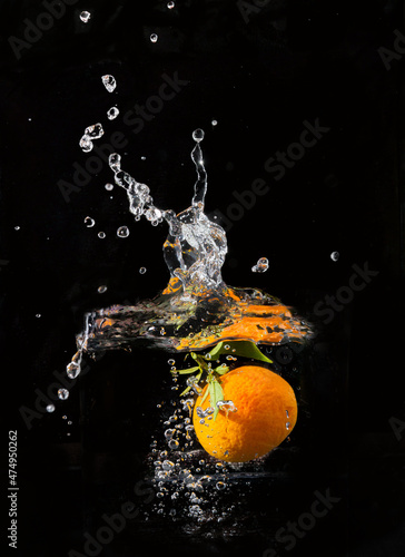 Tangerine with bubbles submerged in water with black background. Vitamin c