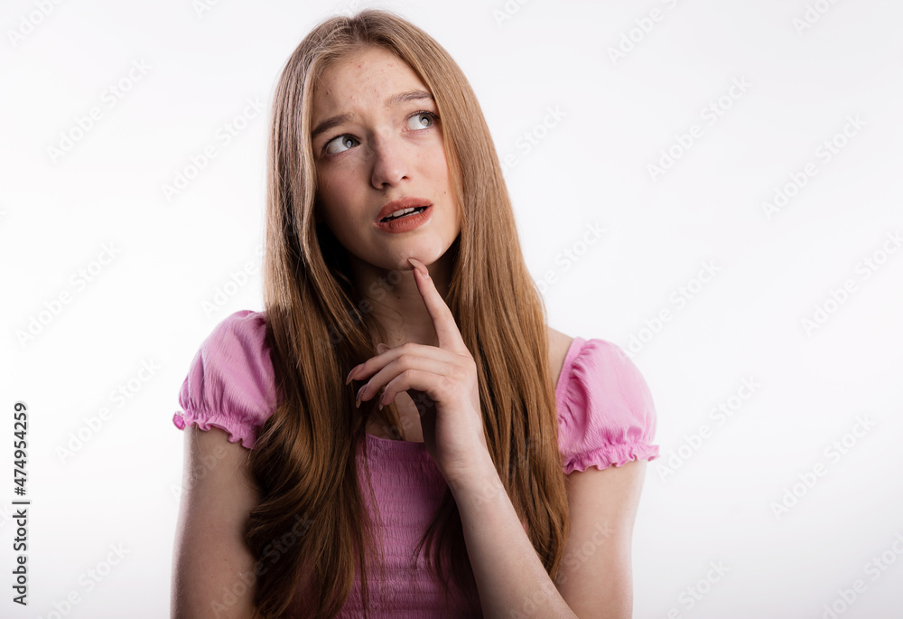 Sad face of a young woman with acne on forehead. She is upset and wrinkled her forehead holds his finger near face and thinking about something on white background copy space.