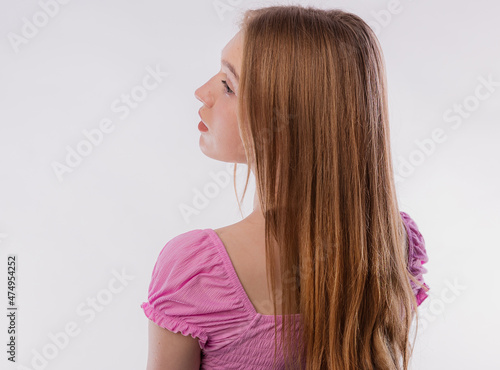 Rear view of a young blonde woman with long hair. Female looking to side isolated on white background copy space. Beautiful and healthy hair, care and coloring.