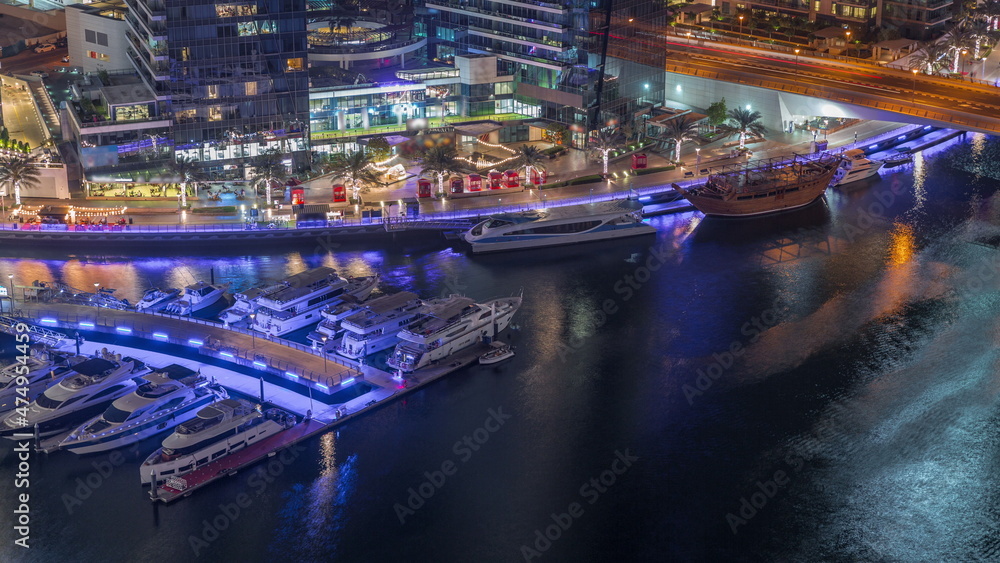 Obraz premium Dubai marina promenade on waterfront along canal aerial night timelapse.