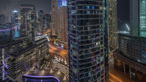 Aerial view to Dubai marina skyscrapers around canal with floating boats night timelapse photo