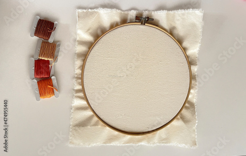 
Wooden embroidery hoop with clean white fabric and earth tones threads photo