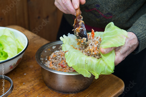 real cooking at home: man adding boiled Buckwheat and fried vegetables to cabbage leaf for vegetarian golubtsi, traditional russian cabbage rolls photo
