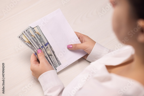Successful business person takes an envelope with 100 dollar banknotes. Counting hundred dollar banknotes. Illegal deal with money. Corruption. Envelope salary. Tax cheating