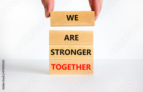 We are stronger together symbol. Concept words We are stronger together on wooden blocks. Businessman hand. Beautiful white background, copy space. Business and we are stronger together concept. photo