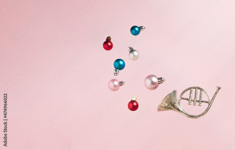 Silver trumpet with colorful Christmas baubles against pastel pink background. Advertisement idea. Minimal New Year concept.  Creative Holiday party concept. Copy space.