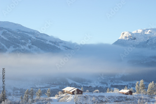 Beautiful morning aerial view on norwegian ski resort with mountains in fog and farm hoses,tree covered with frost in Hemsedal,Norway,print for wall canvas,calendar,postcard,idyllyc place for relax. photo