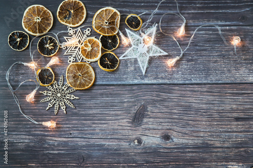 Dried orange slices, thread stars, cut snowflakes, garland on a wooden table. Place for your text. Shooting from above. Copy space