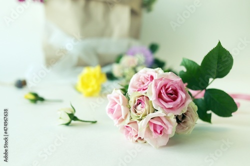 Bouquet of fresh roses  a package with flowers on a light background with a place for an inscription  the concept of a romantic congratulation  invitation  wedding  postcard  Valentines  shop