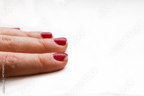 Vászonkép Red chipped nail polish on woman's fingernails holding pencil in office