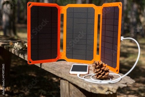 Smartphone is charging from solar battery in summer camping. Clean energy for using in a camp.