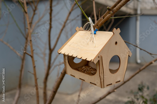 Hanging small decorative yellow birdhouse in the natural green environment. Outdoor empty wood home for birds