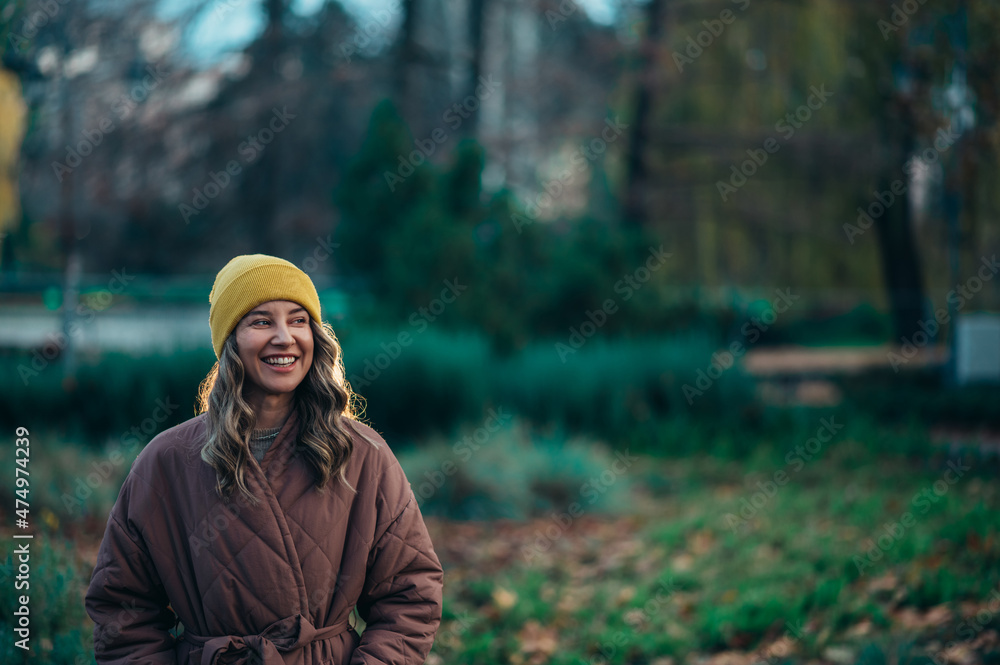 Beautiful young stylish woman wearing coat and a cap in the park