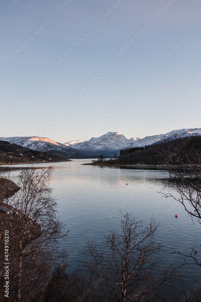 Snowy mountain hills overlooking Lake Rombaken near the town of Narvik in northern Norway, Scandinavia. The last slivers of sunset falling on the white mountain peaks.