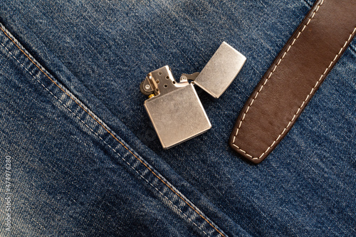 Vintage metal lighter and leather belt on denim