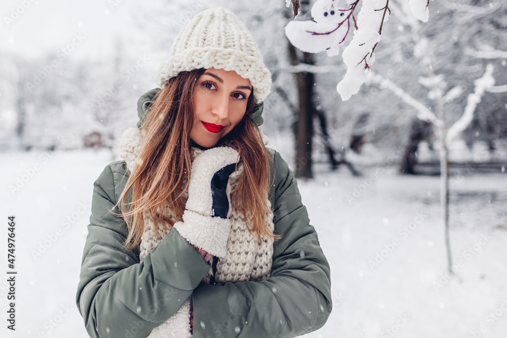 Portrait of beautiful young woman in snowy winter park wearing warm knitted clothes and red festive lipstick. Portrait of beautiful young woman in snowy winter park wearing warm knitted clothes and red festive lipstick.