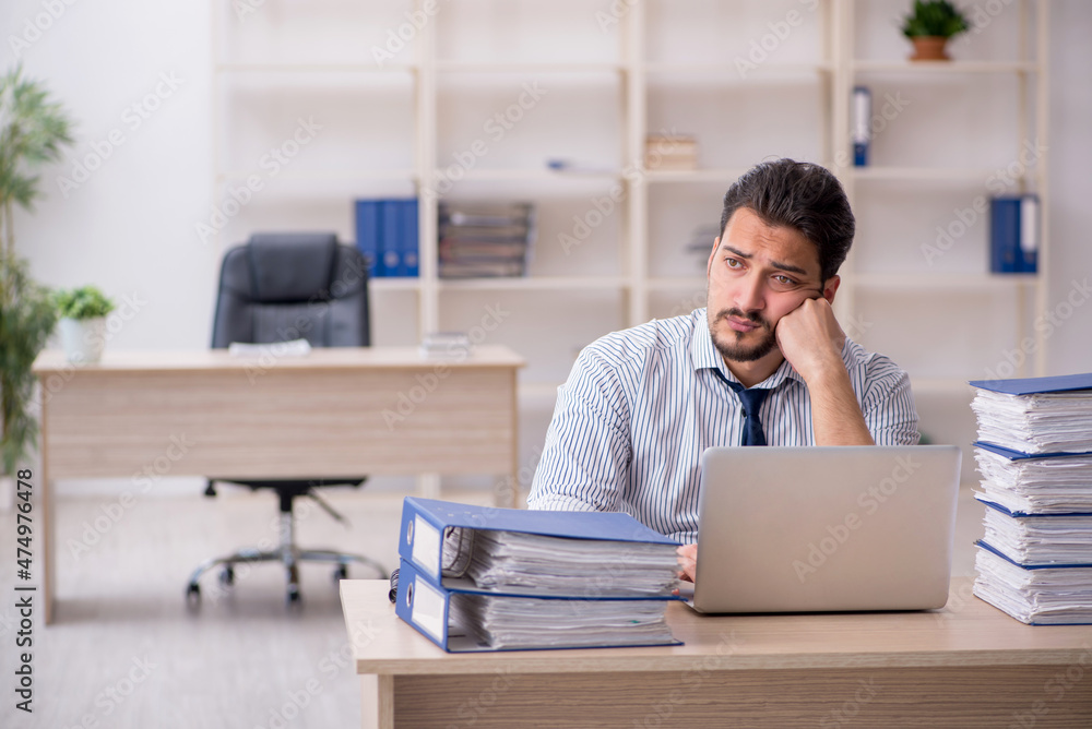 Young male employee and too much work in the office Young male employee and too much work in the office