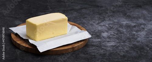 Cuadro en lienzo Freshly unwrapped block of butter on cutting board with copy space
