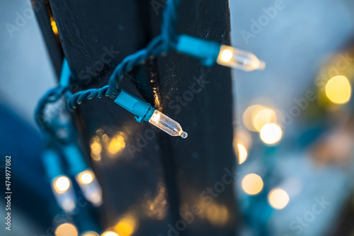 dynamic closeup of festive string lights hung around an iron gate during the holiday season with a blue and yellow backdrop