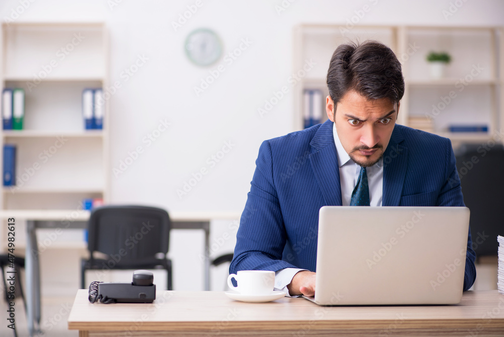 Young male employee and too much work in the office Young male employee and too much work in the office