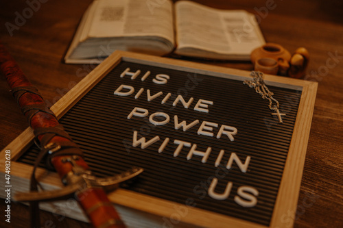 Letterboard with bible, sword, cross necklace and brown themed. His divine power within us 