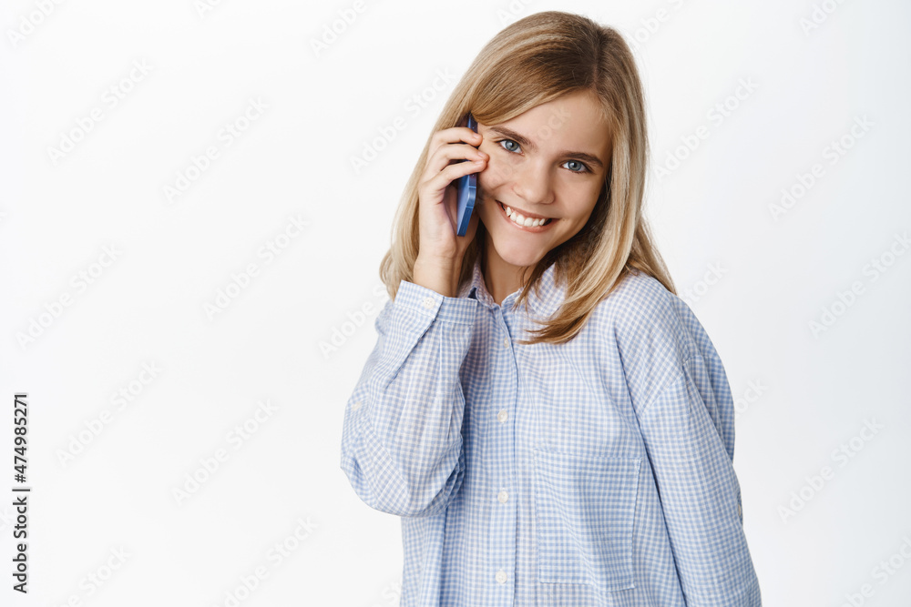 Cute little girl, beautiful blond kid talking on mobile phone, having conversation on smartphone, answer a call, standing over white background Cute little girl, beautiful blond kid talking on mobile phone, having conversation on smartphone, answer a call, standing over white background