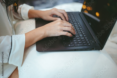 young Asian woman using laptop computer to business online work, female freelance working from home by using internet cyberspace communication technology for businesswoman job