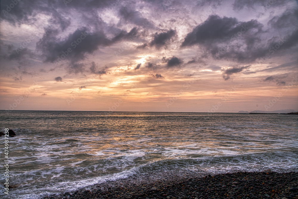 Obraz premium Backlit sunset photo from the rocky shore.