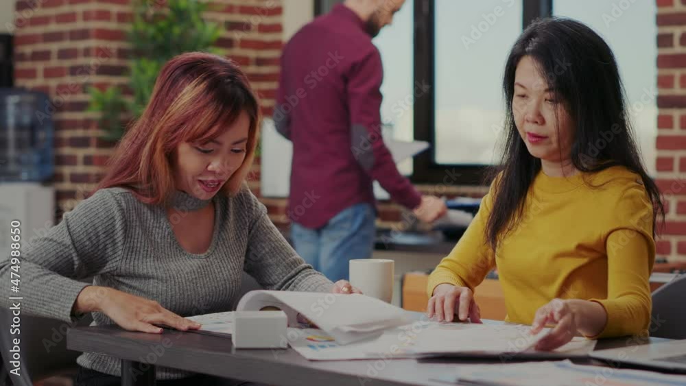 Business partners working with e commerce statistics in office. Team of asian women analyzing financial graphs to develop sales growth and marketing presentation. Workers briefing ideas Business partners working with e commerce statistics in office. Team of asian women analyzing financial graphs to develop sales growth and marketing presentation. Workers briefing ideas