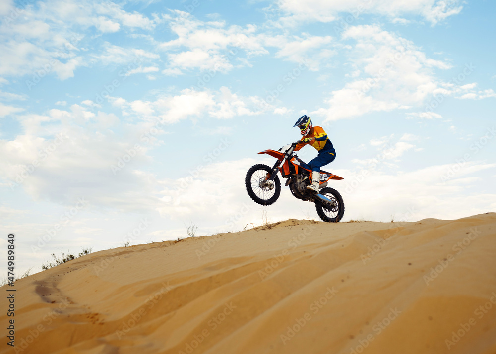 Motorcross riding over sand in desert dune