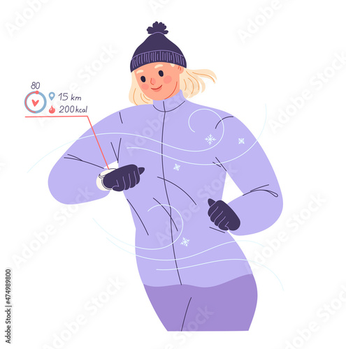 Woman runs outside in winter and looks at smart watch checking her heart rate, pulse, calories, distance.