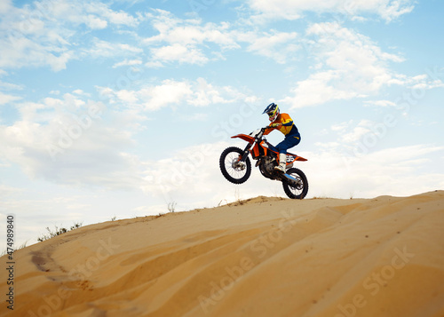 Motorcross riding over sand in desert dune