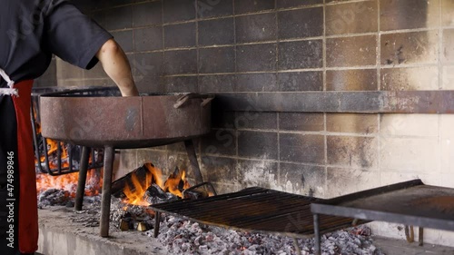 Chef aceitando disco sobre fuego para la preparación de comida típica sudamericana photo