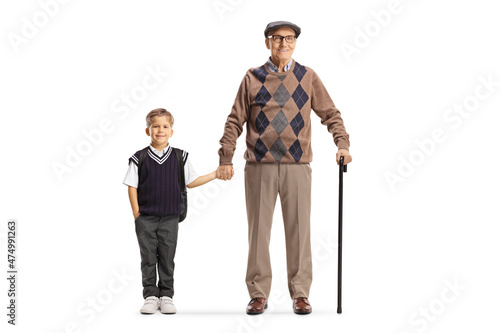 Full length portrait of a grandfather and schoolboy standing and holding hands