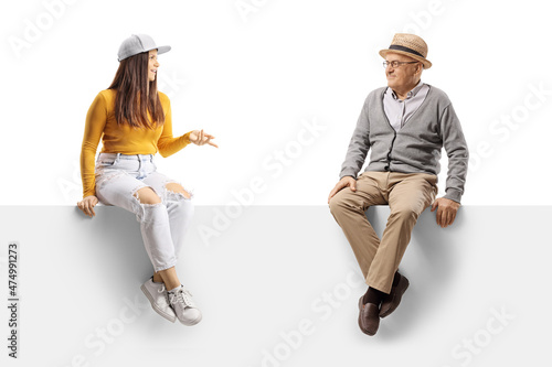 Elderly man listening to a young female seated on a blank panel