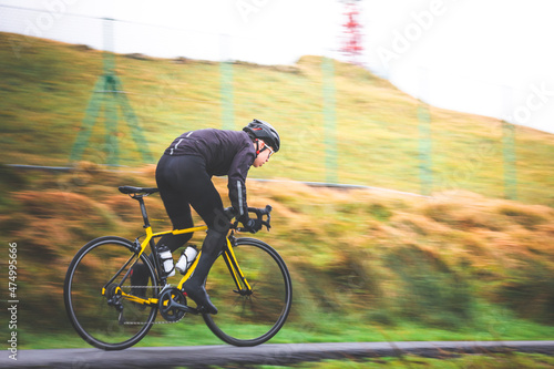 Fotografi Pan shot of a young caucasian cyclist man sprinting on his bike.