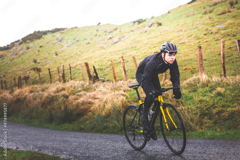 Fototapeta premium Young caucasian cyclist man climbing a hill in a foggy mountain.