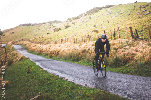 Young caucasian cyclist man climbing a hill in a foggy mountain.