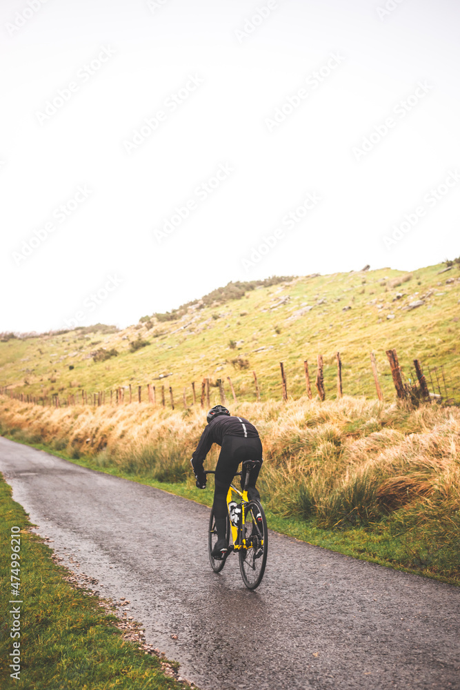 Fototapeta premium Young caucasian man going downhill with a road bike on an asphalt road of a mountain.