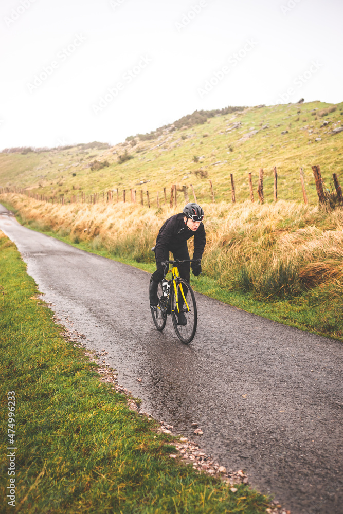 Fototapeta premium Young caucasian cyclist man climbing a hill in a foggy mountain.
