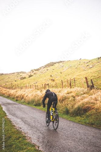 Young caucasian man going downhill with a road bike on an asphalt road of a mountain. © Jorge Argazkiak